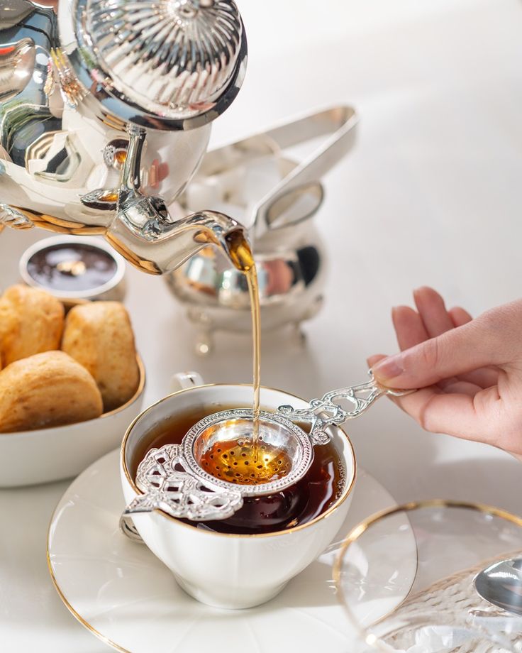 Tea poured through a silver strainer into a fine china cup